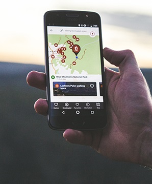 A man uses the NPWS app on a mobile phone at sunrise in Blue Mountains National Park. Photo: Daniel Parsons/DPIE