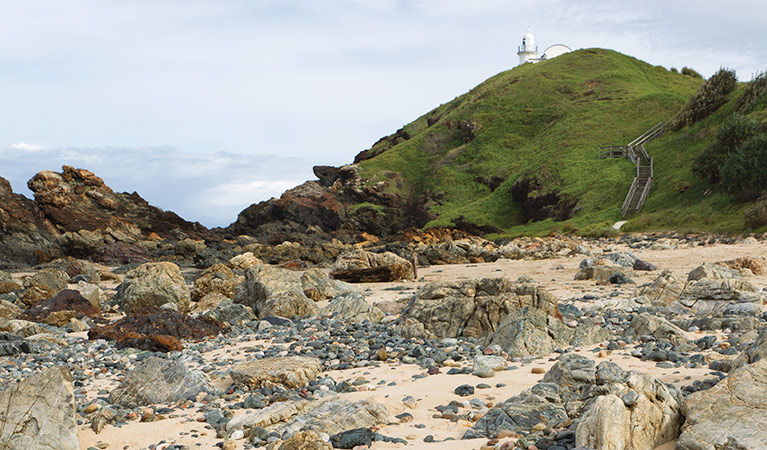 Rocky coastline with a distant lighthouse, Sea Acres National Park. Photo: Rob Cleary